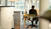 A woman sitting at a desk with her back to the camera.