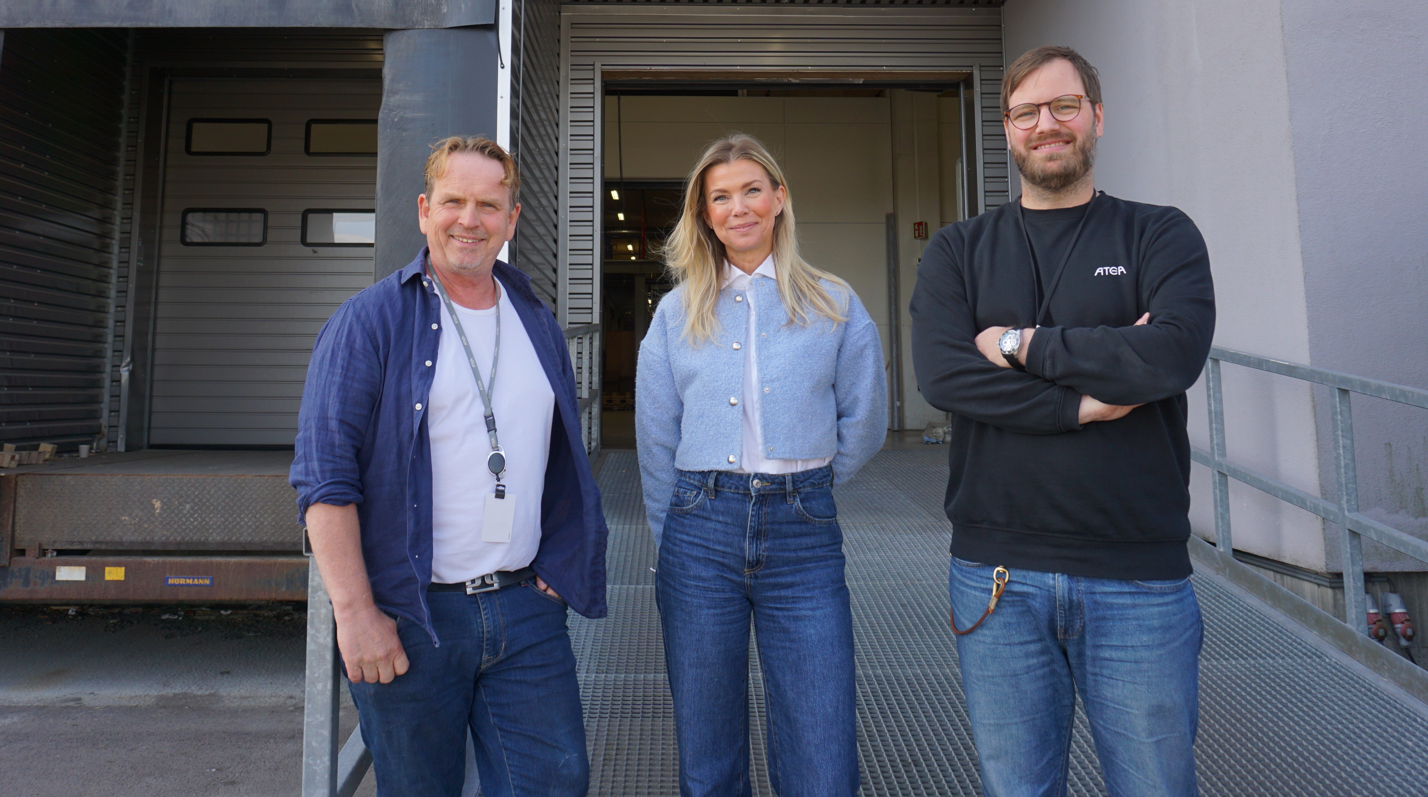 Tre personer står foran et bygg