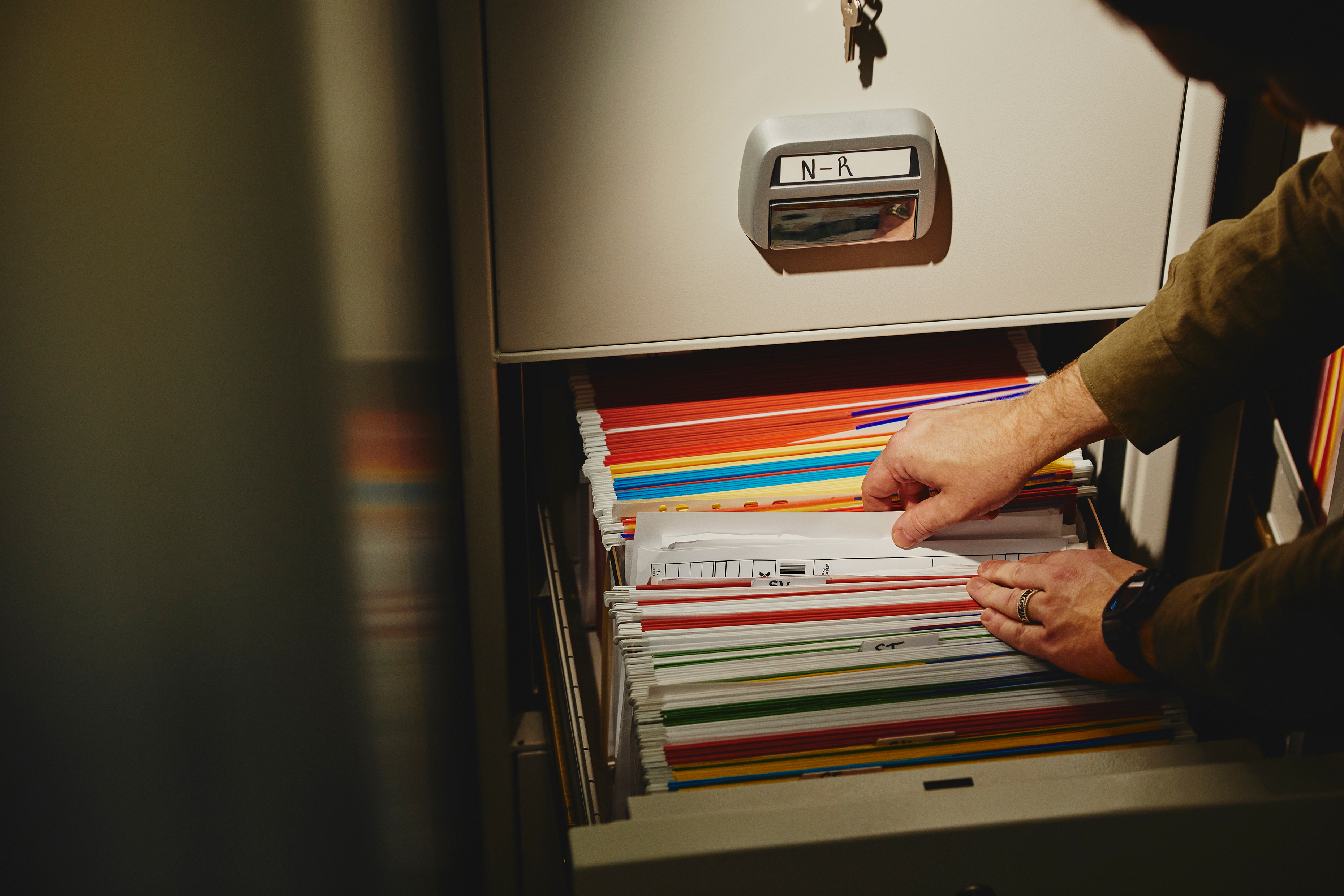 Työntekijä käy arkistokaapin tiedostoja läpi