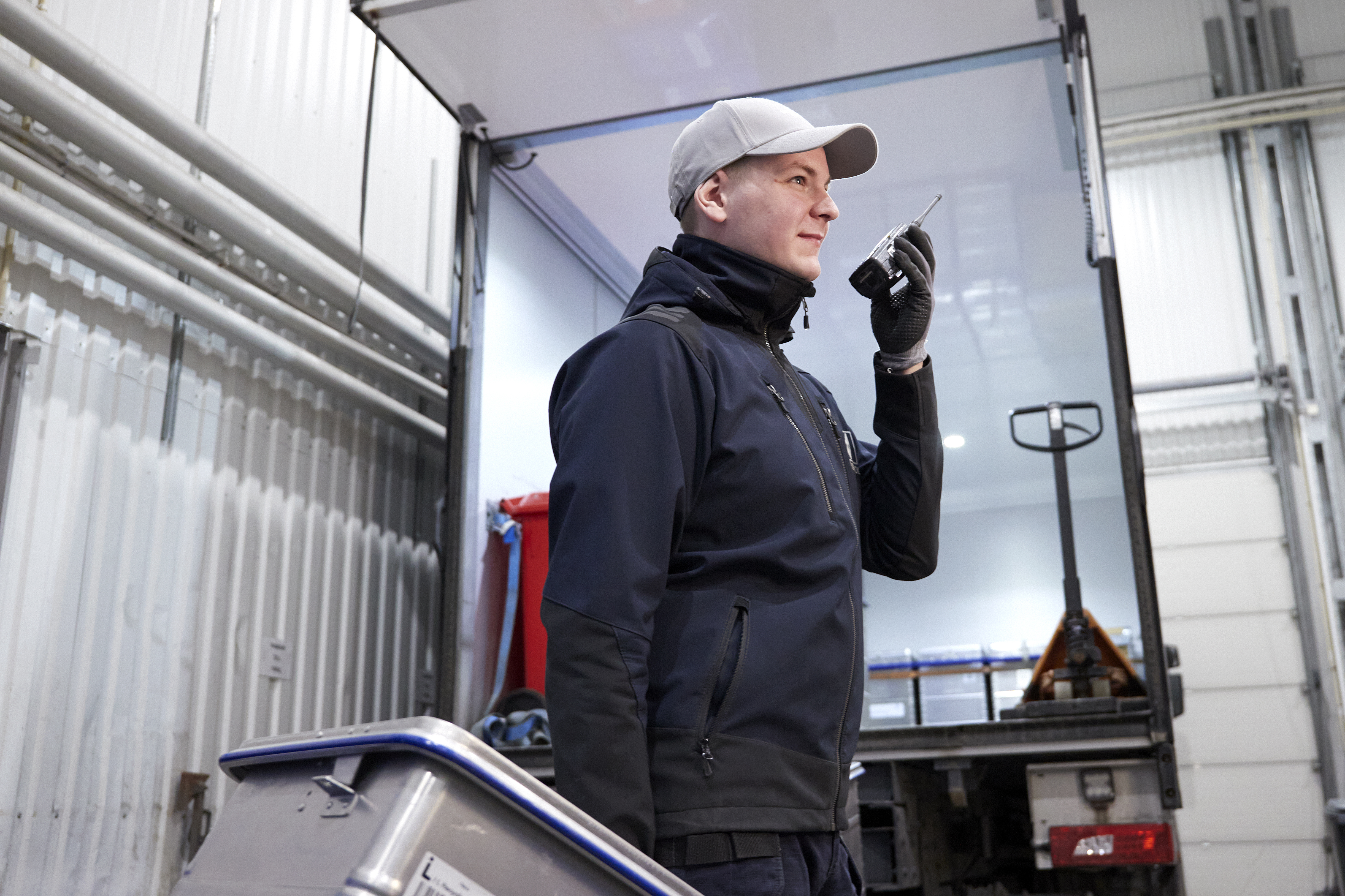 Man med keps som håller i ett säkerhetskärl med en lastbil i bakgrunden